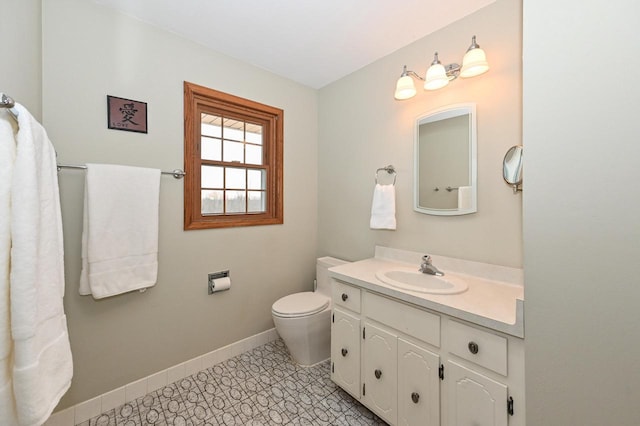 bathroom with toilet, baseboards, and vanity