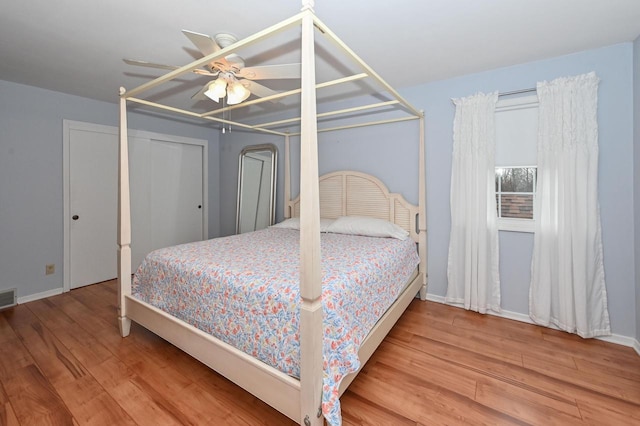 bedroom with a ceiling fan, baseboards, visible vents, and wood finished floors