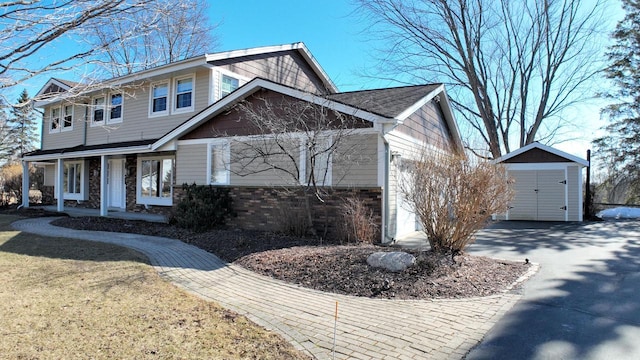 view of front facade featuring a porch, aphalt driveway, a garage, an outdoor structure, and a storage unit