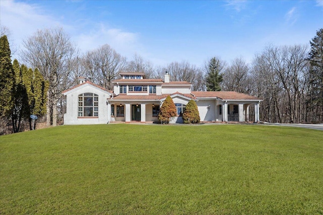 view of front facade with a porch, a chimney, and a front lawn