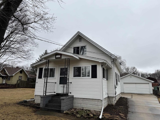 bungalow-style home featuring a detached garage, a front lawn, and an outdoor structure