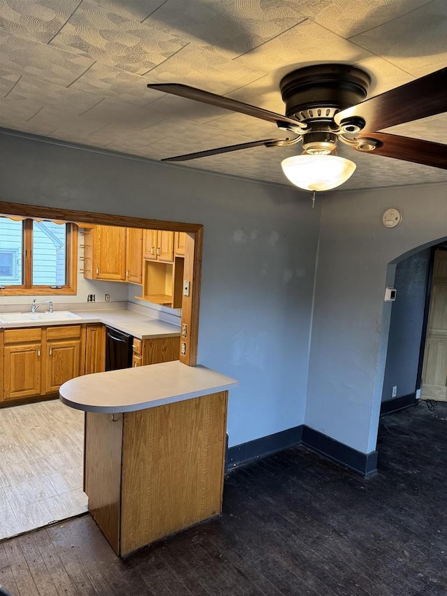 kitchen featuring a sink, baseboards, black dishwasher, light countertops, and dark wood-style floors