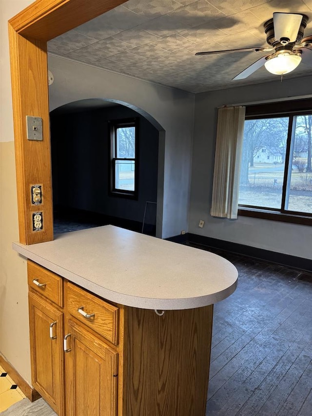 kitchen with a peninsula, a healthy amount of sunlight, light countertops, and brown cabinets