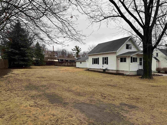 back of house with fence and a lawn