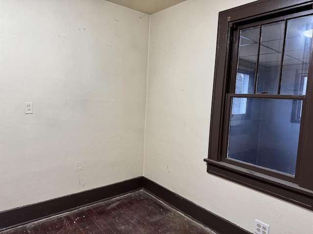 spare room featuring hardwood / wood-style flooring and baseboards