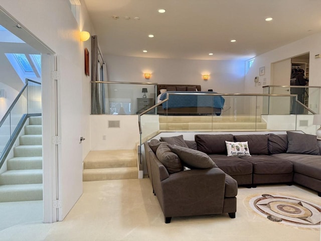 living room with a skylight, stairway, light colored carpet, and recessed lighting