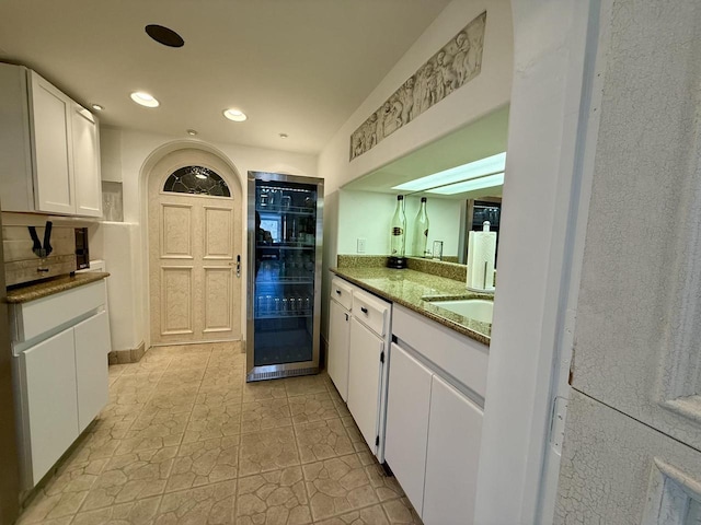 kitchen with dark stone counters, wine cooler, white cabinetry, and recessed lighting