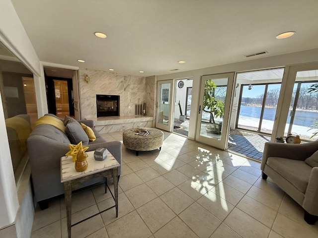 living area featuring light tile patterned floors, a high end fireplace, visible vents, and recessed lighting