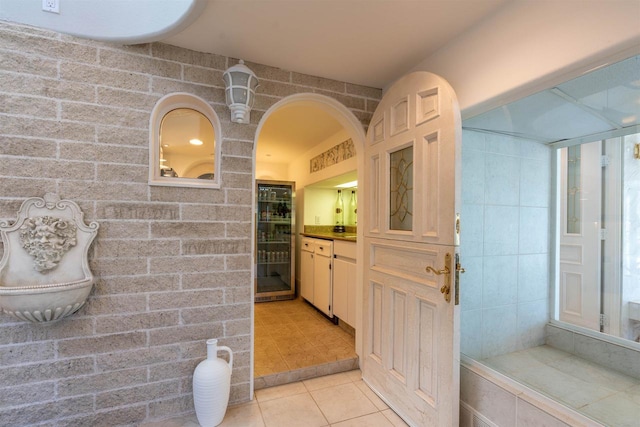 bathroom featuring brick wall, tile patterned flooring, and vanity