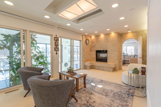 living room with a premium fireplace, visible vents, arched walkways, and recessed lighting