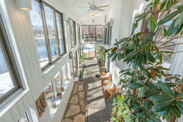 sunroom with lofted ceiling, a water view, and a ceiling fan