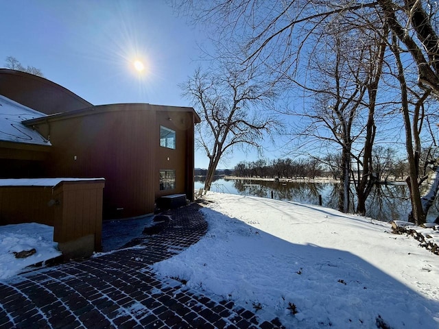 yard covered in snow featuring a water view