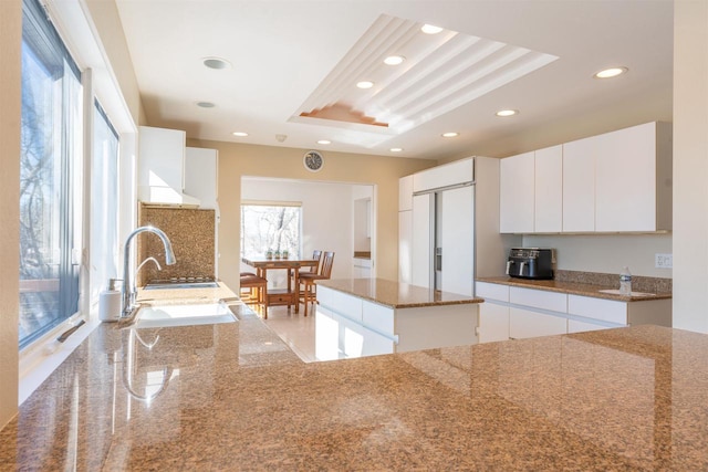 kitchen featuring paneled built in fridge, stone counters, white cabinetry, a sink, and recessed lighting