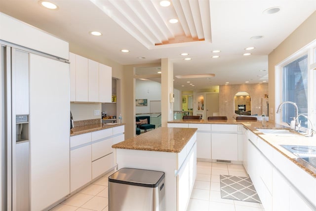 kitchen featuring light tile patterned floors, recessed lighting, a sink, white cabinets, and a center island