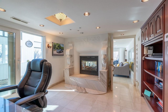 home office with a healthy amount of sunlight, recessed lighting, visible vents, and a multi sided fireplace