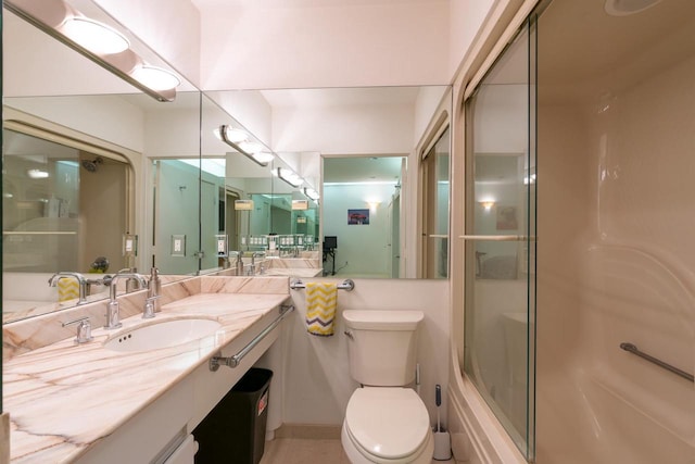 full bath featuring toilet, vanity, and a shower with door