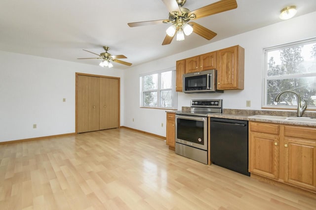 kitchen featuring stainless steel appliances, light wood-type flooring, a sink, and baseboards