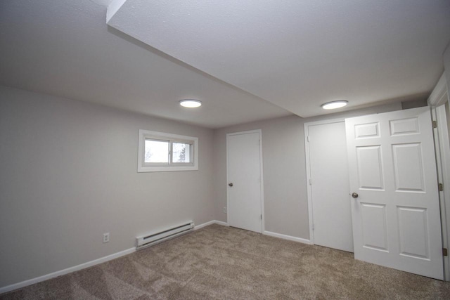 below grade area featuring baseboard heating, carpet flooring, and baseboards