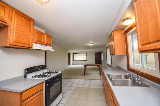 kitchen with gas stove, open floor plan, light carpet, a sink, and under cabinet range hood