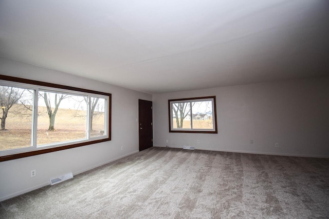 carpeted spare room featuring visible vents and baseboards