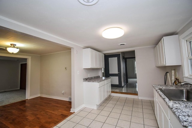 kitchen featuring ornamental molding, light tile patterned flooring, a sink, and white cabinets