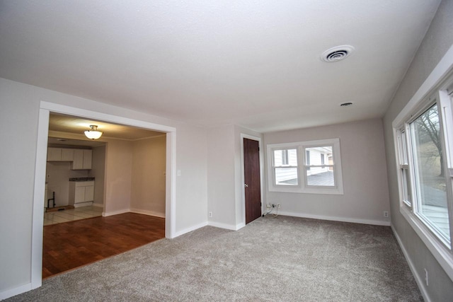 carpeted empty room featuring visible vents and baseboards