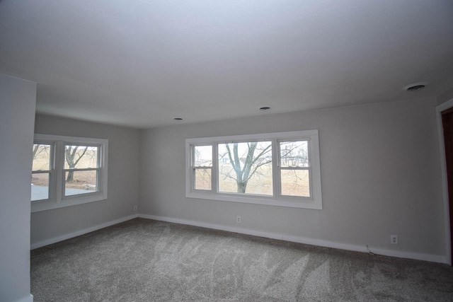 spare room with carpet flooring, visible vents, and baseboards