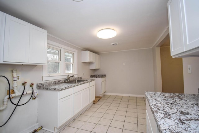 kitchen featuring white cabinetry, a sink, baseboards, and light tile patterned floors