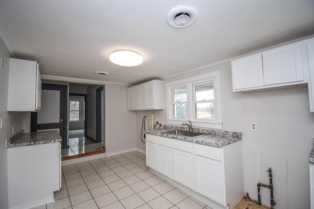 kitchen featuring baseboards, light tile patterned flooring, a sink, and white cabinets