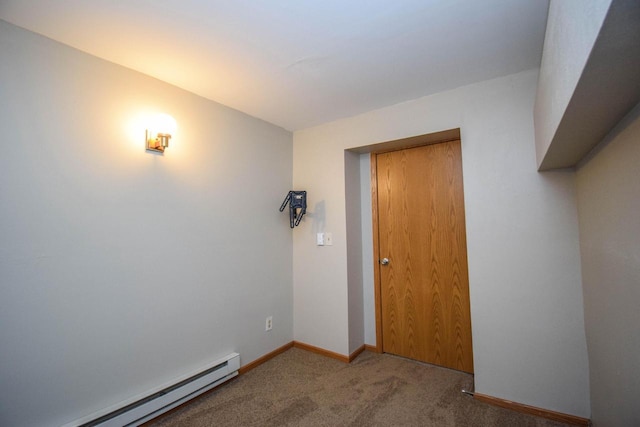 empty room featuring a baseboard heating unit, carpet floors, and baseboards