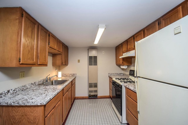 kitchen with range with gas cooktop, light countertops, freestanding refrigerator, a sink, and under cabinet range hood