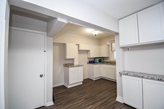 kitchen featuring dark wood-style flooring, white cabinets, baseboards, and light stone countertops