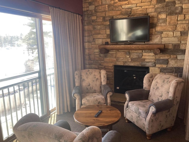 living area with carpet floors and a stone fireplace