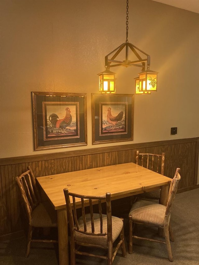 carpeted dining room featuring wainscoting and wooden walls