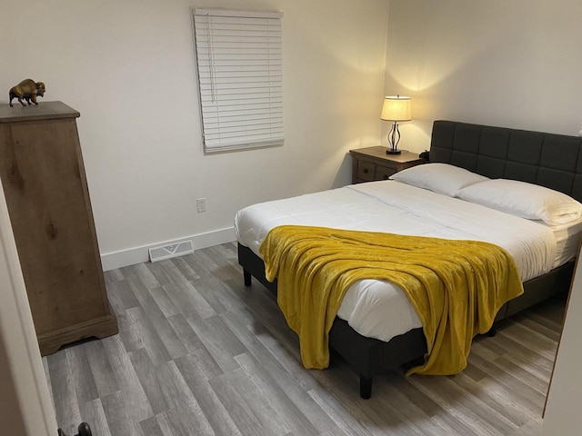 bedroom featuring visible vents, baseboards, and wood finished floors