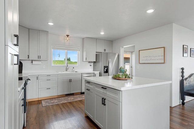 kitchen featuring appliances with stainless steel finishes, light countertops, a sink, and dark wood-style floors