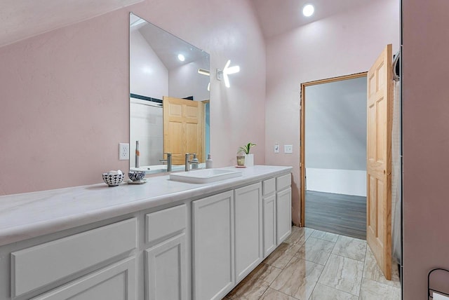 bathroom with marble finish floor, vaulted ceiling, and vanity