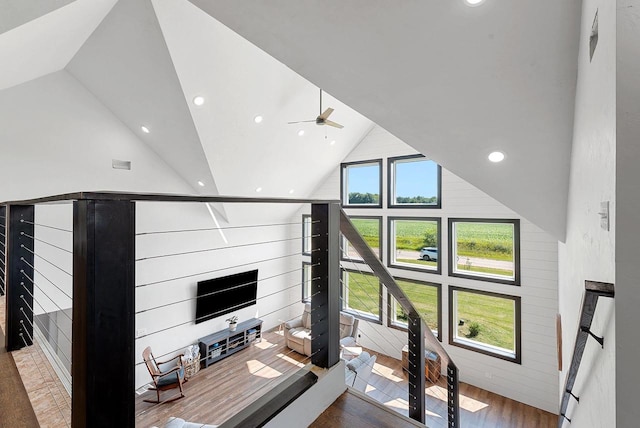 living area with wooden walls, a ceiling fan, wood finished floors, high vaulted ceiling, and recessed lighting