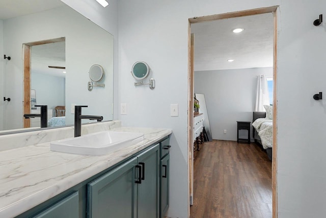 ensuite bathroom featuring recessed lighting, vanity, connected bathroom, and wood finished floors