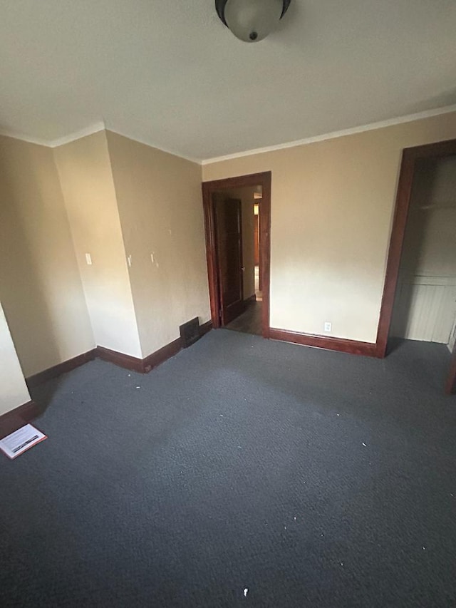 carpeted spare room with ornamental molding, visible vents, and baseboards