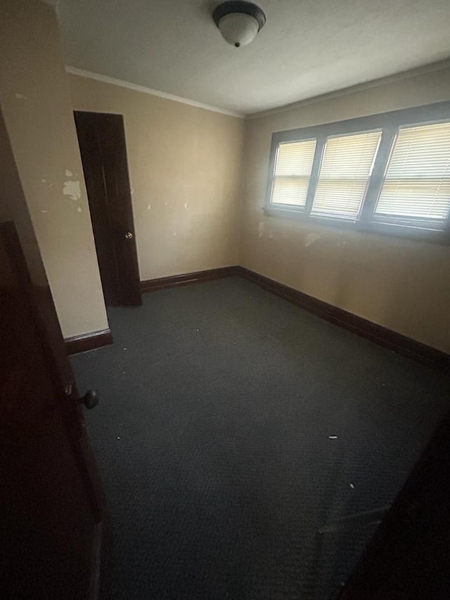 empty room featuring crown molding, carpet floors, and baseboards