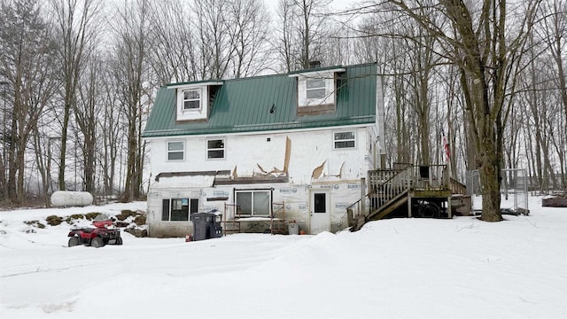 snow covered house with metal roof and stucco siding