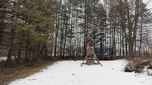 snow covered playground featuring a trampoline and a playground