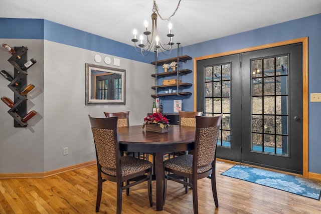 dining area featuring baseboards, an inviting chandelier, and hardwood / wood-style flooring