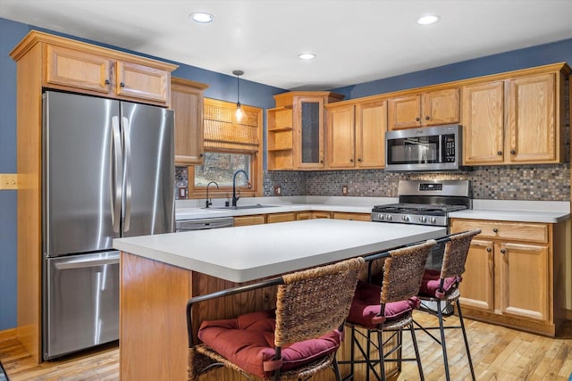 kitchen with light wood finished floors, light countertops, appliances with stainless steel finishes, and a sink