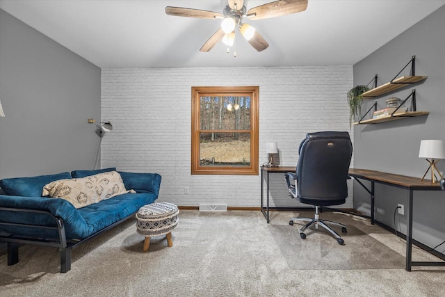 home office with brick wall, visible vents, ceiling fan, and carpet flooring