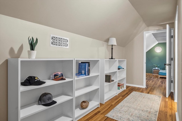 hallway featuring vaulted ceiling, baseboards, and wood finished floors