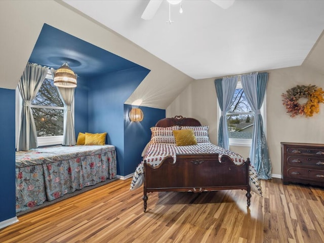 bedroom featuring lofted ceiling, baseboards, and wood finished floors