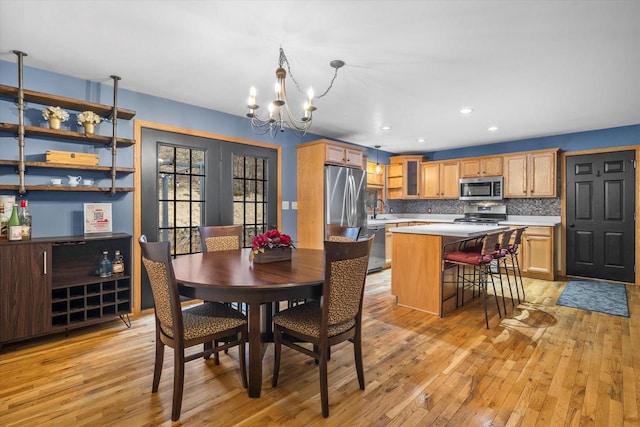 dining space with light wood finished floors, a chandelier, and recessed lighting