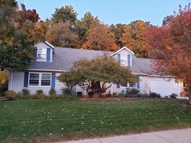 cape cod home featuring a shingled roof and a front yard